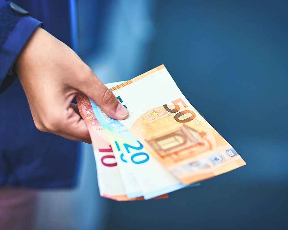Una mano con dinero para pagar factura.